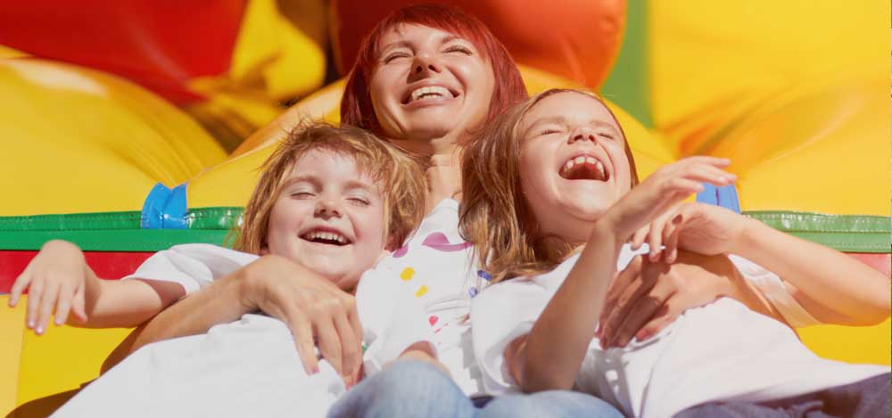 a mother and her two children laying down and laughing in a bounce castle